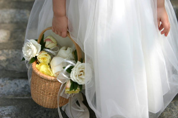A flower girl holds a basket of flowers before a wedding ceremony